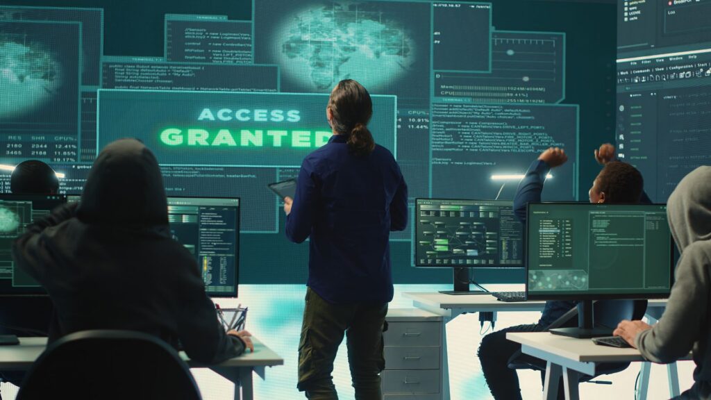 A group of people at computer workstations look at a large screen displaying "Access Granted," enhanced by digital interface graphics and Cybersecurity Animation in the background.