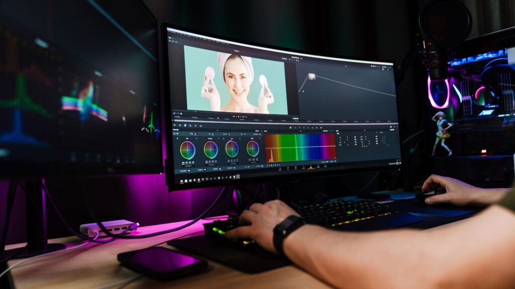 Person editing a Change Management Animation video of a woman holding skincare products on a curved monitor, with color grading tools and color wheels visible on the screen.