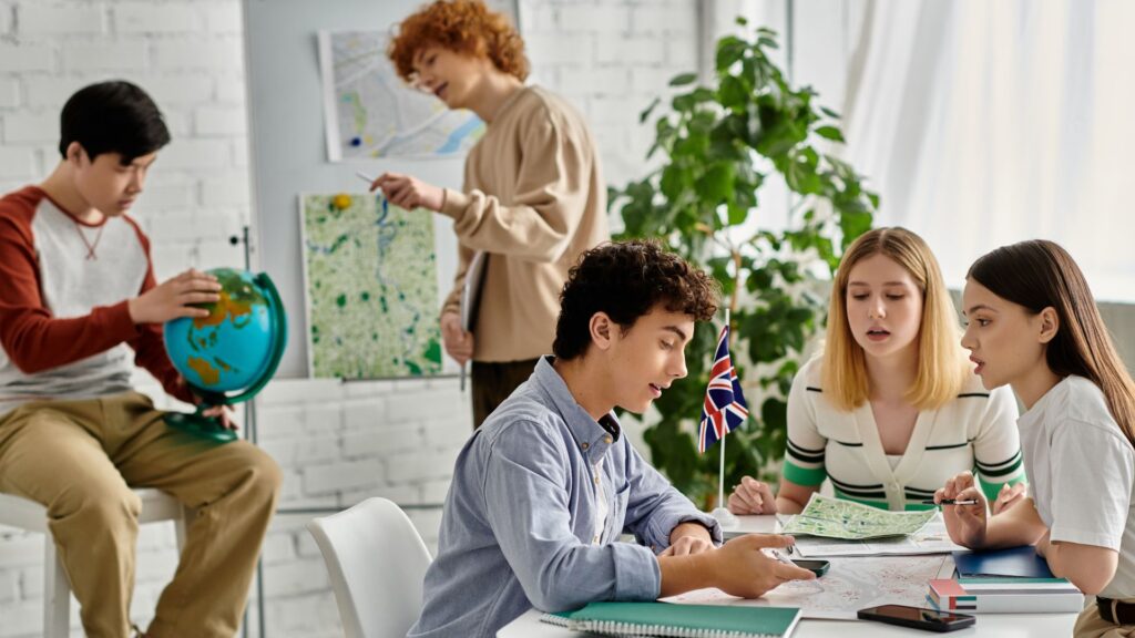 Five students in a classroom study maps and a globe, with one holding a small UK flag; this scene captures an engaging moment of Educational Animation within an educational institution, as students actively participate in learning geography.