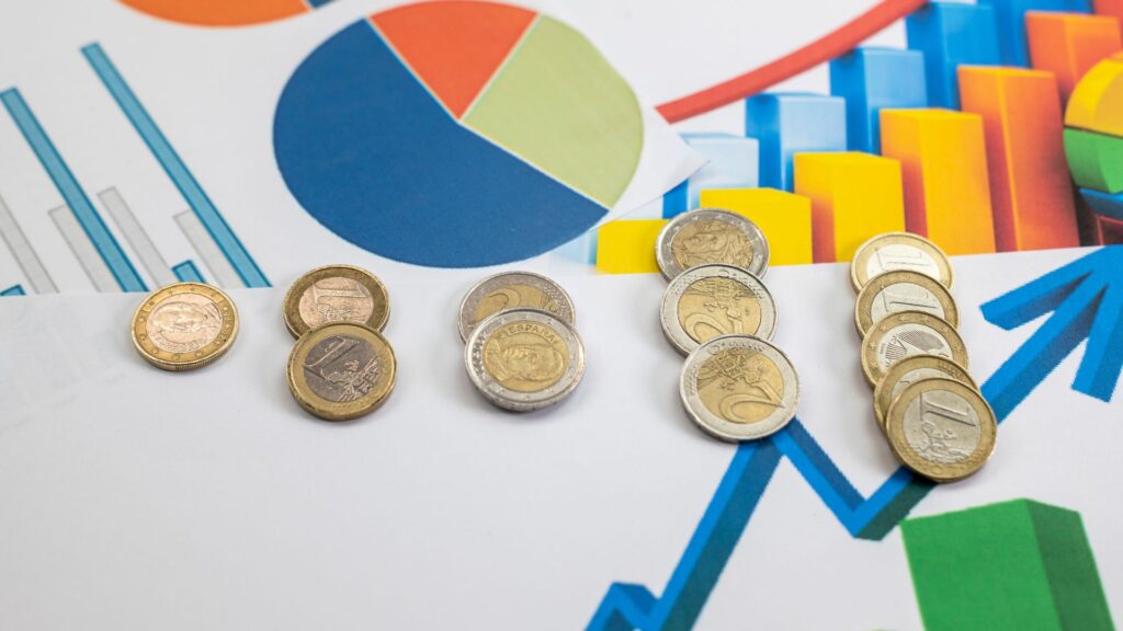 Euro coins are arranged in groups on top of colorful financial charts, including bar graphs and pie charts, creating a striking visual ideal for a video animation about economics.