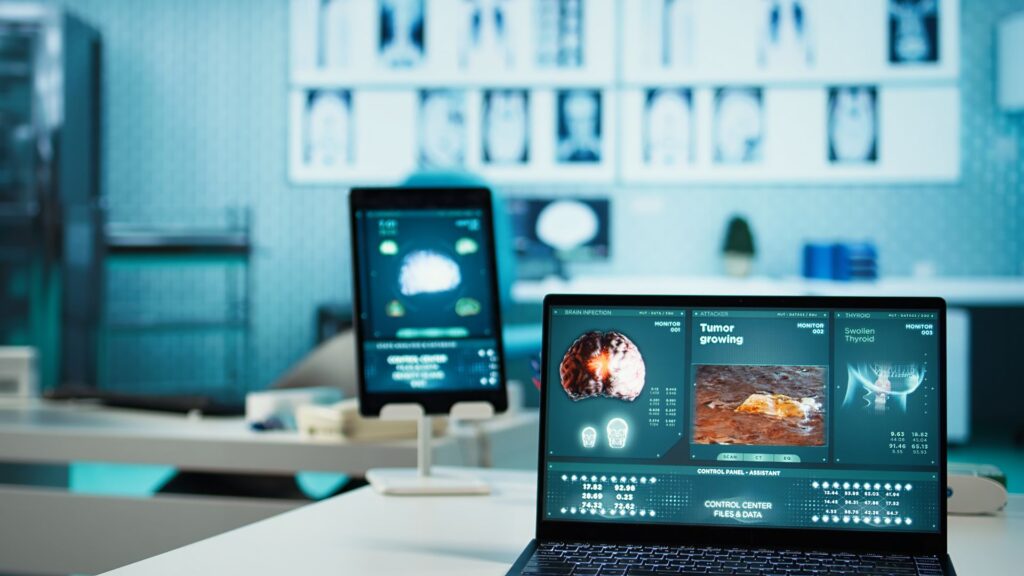 A laptop screen displays medical imaging and data about a growing tumor, alongside an Animation Software Comparison, in a modern, high-tech clinic or hospital setting.