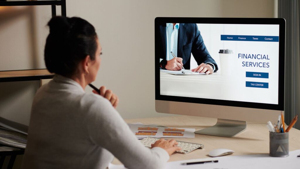 Person sitting at a desk looking at a computer screen displaying a financial services website with sign-in and talk cover options, enhanced by engaging Banking Animation Videos.