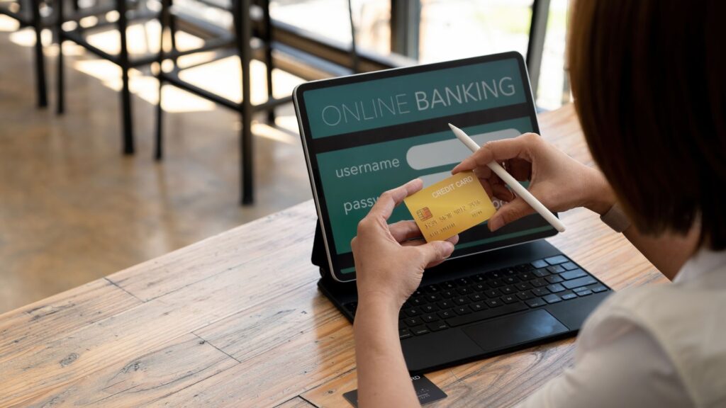 A person holds a credit card and stylus in front of a tablet displaying an online banking login screen on a wooden table, evoking scenes often depicted in Banking Animation Videos.
