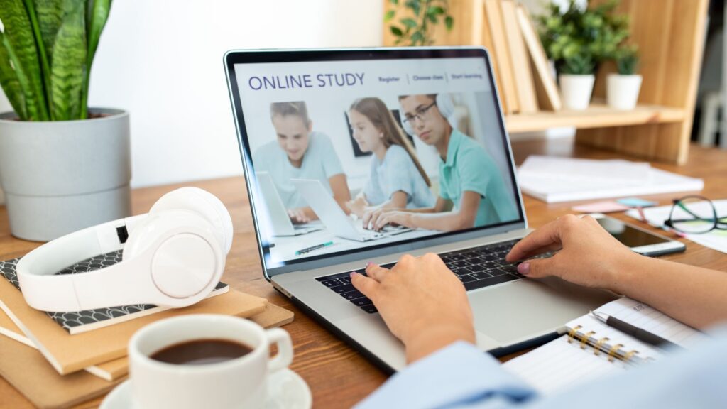Person using a laptop displaying an "Online Study" webpage with engaging Animation for Website; headphones, coffee, and stationery are neatly arranged on the wooden desk.