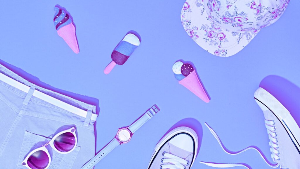 Flat lay of summer accessories on a blue background, featuring sunglasses, shorts, sneakers, a watch, floral cap, and ice cream-shaped toys—ideal inspiration for an engaging Engagement Guide or playful Product Explanation Animation.