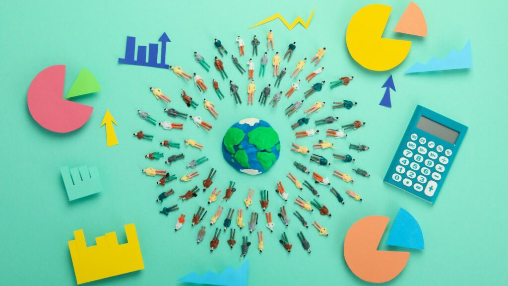 Miniature figures form a circle around a model Earth, surrounded by paper graphs, pie charts, and a calculator on a teal background, illustrating visual learning and data analysis within a global community.