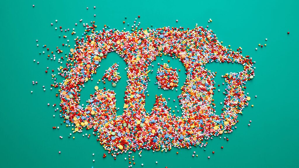 The word "ART" is spelled out in negative space surrounded by scattered colorful candy sprinkles on a teal background, resembling kinetic typography animation techniques.