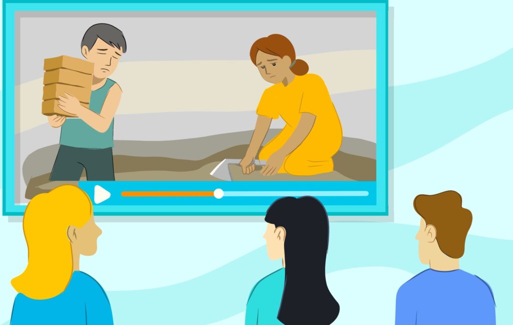 Four people watch a video showing a man carrying bricks and a woman kneeling and working on the ground.